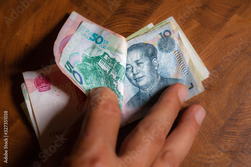 Male hand shows Renminbi or Chinese yuan  or abbreviated RMB banknote, the official currency of the peoples republic of china. On front side the portrait of Mao Zedong,  Close up Paper Money of china photo