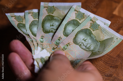 Male hand with a fan of 1 Renminbi or Chinese yuan  or abbreviated RMB banknote, the official currency of the peoples republic of china. On front side the portrait of Mao Zedong,  Paper Money of china photo