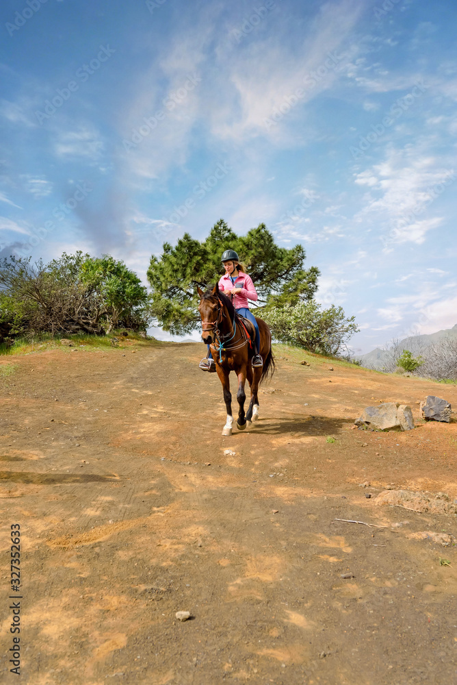 Obraz premium young woman walking and discovering the volcanic landscapes of Tenerife on horseback