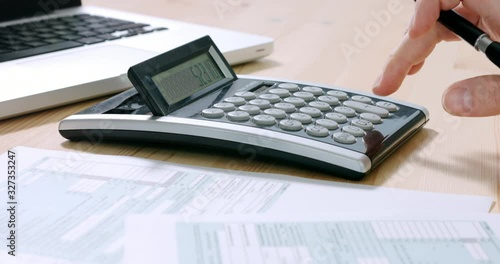 Closeup of US tax form 1040 and businessman hand calculating and filling report paper at the office. 4k footage resolution.