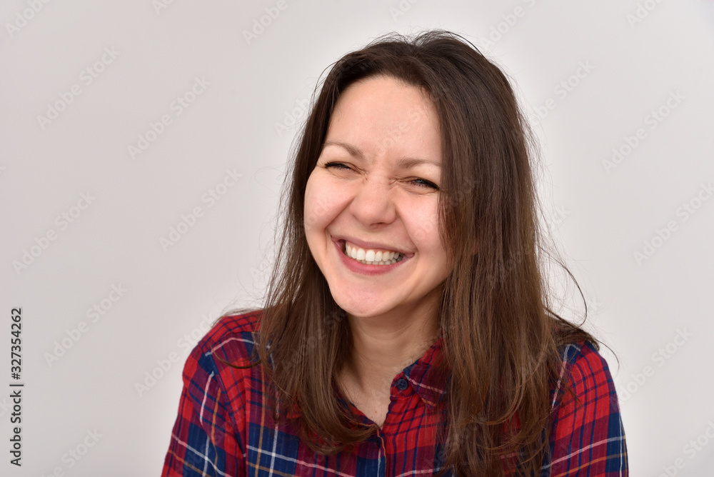 Portrait of a happy smiling beautiful woman with perfect white teeth and long hair wearing plaid shirt. Isolated on the background. Portrait of a happy smiling beautiful woman with perfect white teeth and long hair wearing plaid shirt. Isolated on the background.
