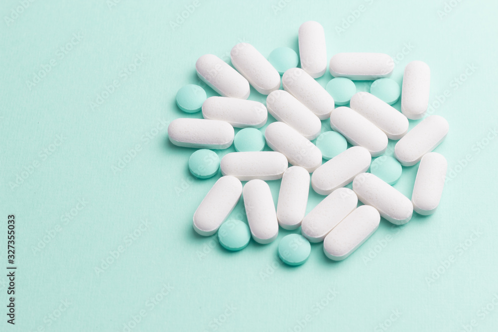 White and green pills against green background White and green pills against green background