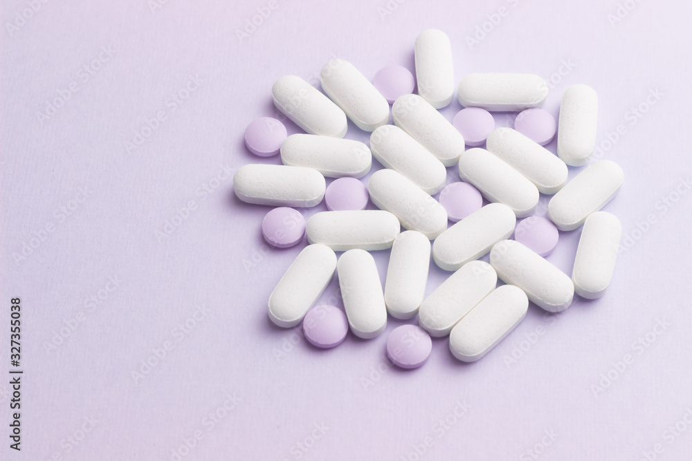White and lilac pills against lilac background