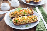 Baked stuffed eggplant with minced meat with cheese on a white plate on a wooden table, selective focus