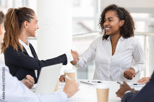 Happy young attractive black woman handshaking with white businesswoman
