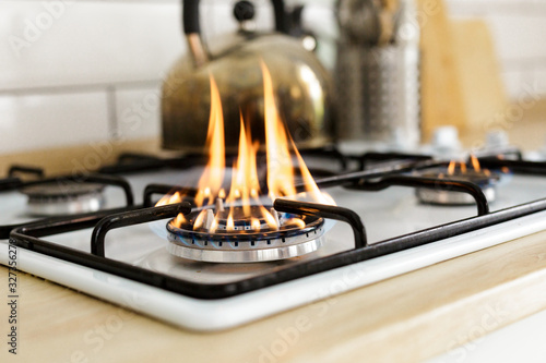 Macro closeup of modern luxury gas stove top with blue fire flame knobs bokeh blurry blurred background