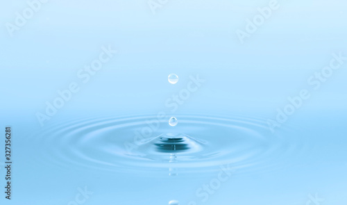 Two water drops and circle ripple, light blue water, close up