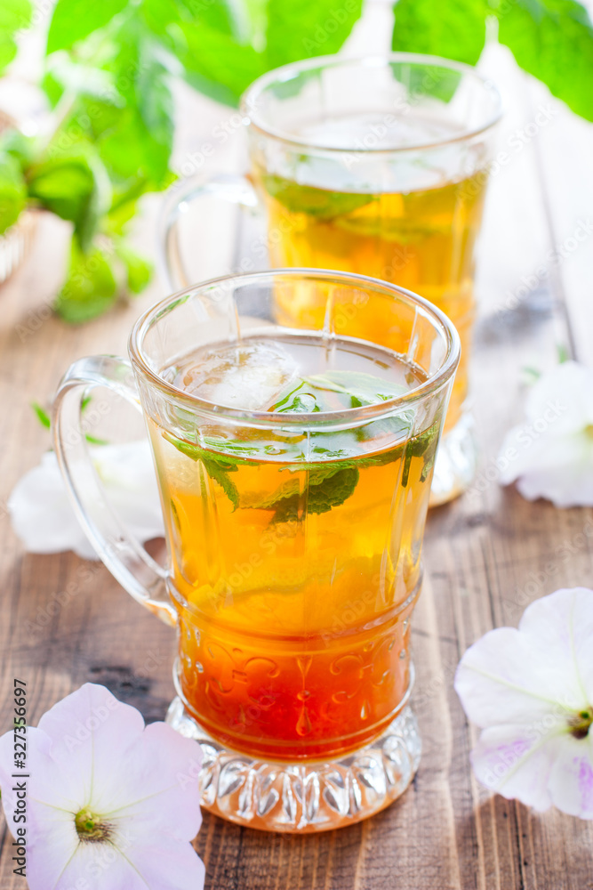 Black iced tea with lemon and mint in glass cups on a wooden table, selective focus Black iced tea with lemon and mint in glass cups on a wooden table, selective focus