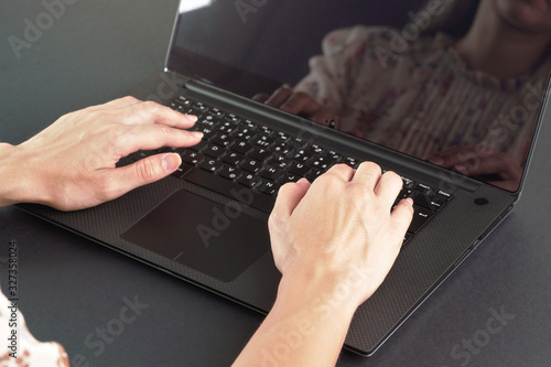 Young female working with laptop computer - detail on her hands over back keyboard