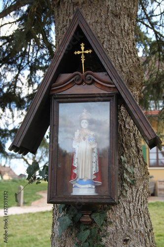 Sacred catholic figurine on a tree trunk © Estelle R