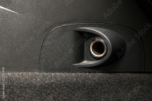 Empty cigarette lighter socket in a car on a black plastic panel. photo