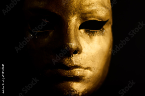 Gold face mask close-up on a black background. Retro style.