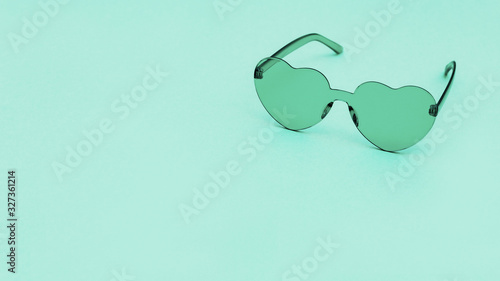 Stylish heart shaped glasses on paper background with copy space. Beautiful trendy turquoise sunglasses. Fashion summer concept.