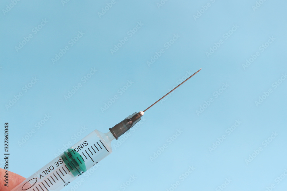 Close up view of syringe with long needle on the blue background. Copy space. Theme of healthcare, vaccination and disease prevention. Close up view of syringe with long needle on the blue background. Copy space. Theme of healthcare, vaccination and disease prevention.