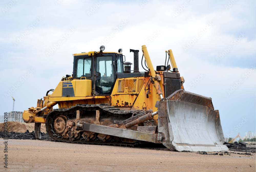 Track-type bulldozer during of large construction jobs at building site. Land clearing, grading, pool excavation, utility trenching, utility trenching and foundation digging. Earth-moving equipment.