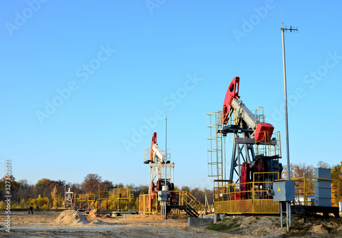 Oil drilling derricks at desert oilfield for fossil fuels output and crude oil production from the ground. Oil drill rig and pump jack on the background, sunset. Belarus, Rechitsa region