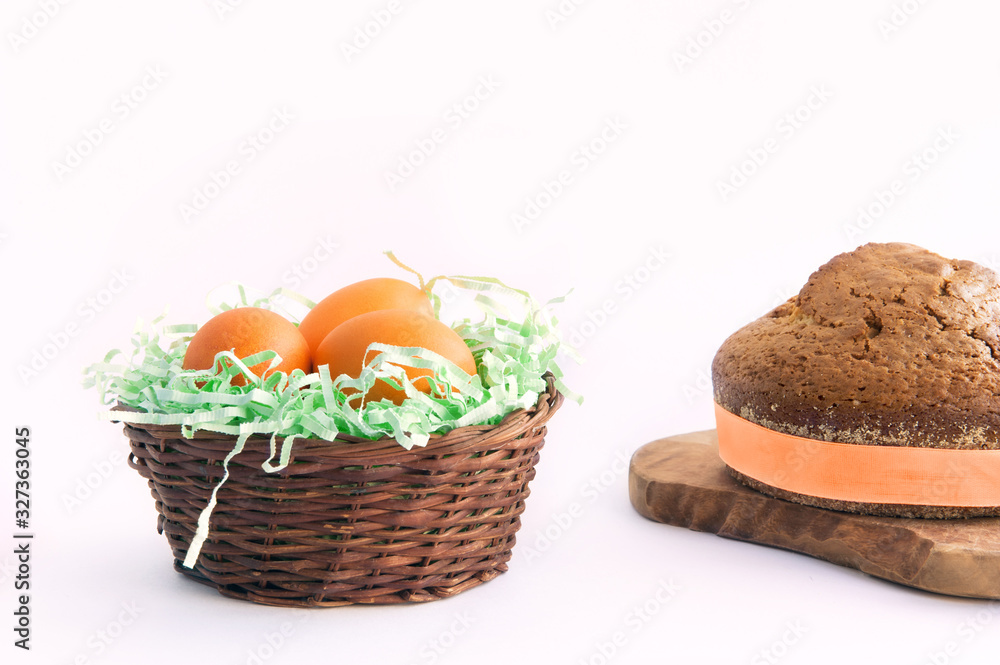 three easter eggs in a wicker basket and a cupcake on a wooden board on a white background three easter eggs in a wicker basket and a cupcake on a wooden board on a white background