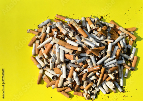 A lot of burnt cigarette butts with some ash. Smoking as a global social problem. Nicotine addiction, anti-smoking.