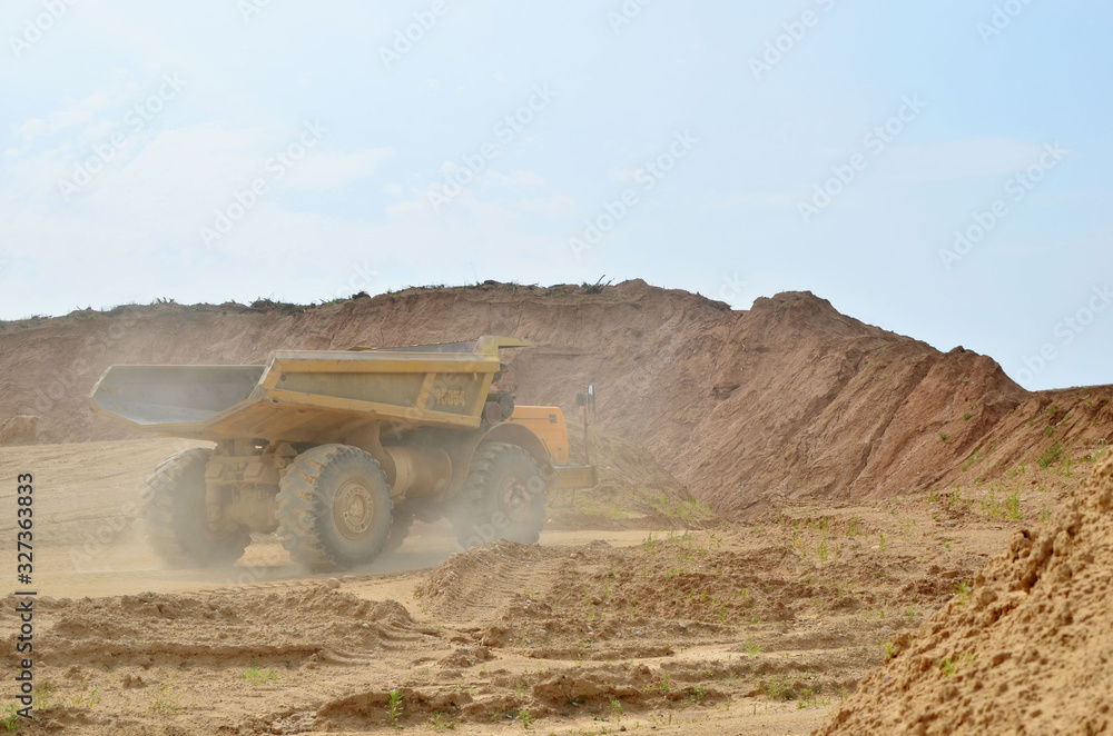 Obraz premium Big yellow dump trucks working in the open-pit. Transporting sand and minerals. Mining quarry for the production of crushed stone, sand and gravel for use in the construction industry - image