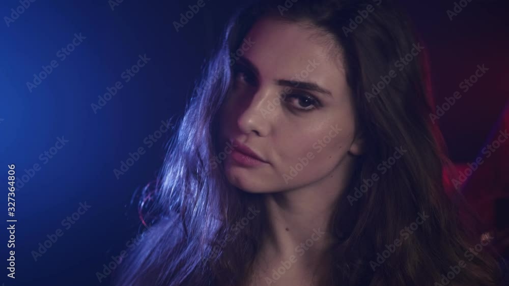 Neon light portrait. Female beauty. Confident brunette girl posing in blue purple colored glow. Neon light portrait. Female beauty. Confident brunette girl posing in blue purple colored glow.