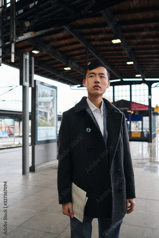 Young stylish Asian businessman in coat confidently waiting subway train Young stylish Asian businessman in coat confidently waiting subway train