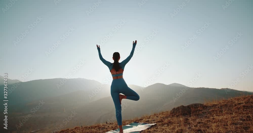 Athletic girl training in mountains during sunrise. Fit model doing various yoga poses during her meditation session - healthy living concept 4k footage