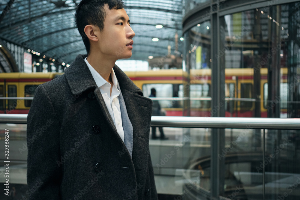 Side view of young Asian businessman thoughtfully looking away at subway station Side view of young Asian businessman thoughtfully looking away at subway station