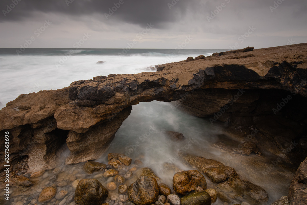 Arch shaped rock formation in the coastline. Long exposure