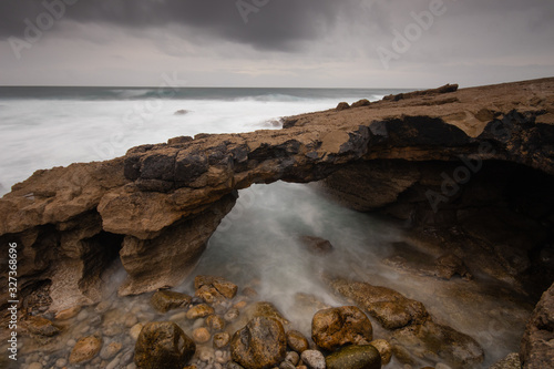 Arch shaped rock formation in the coastline. Long exposure