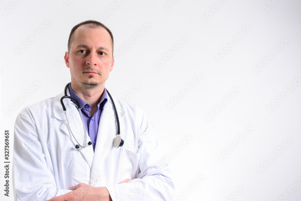 Male doctor with arms crossed and looking at camera while standing against white background. Caucasian male doctor with arms crossed. Male doctor with arms crossed and looking at camera while standing against white background. Caucasian male doctor with arms crossed.