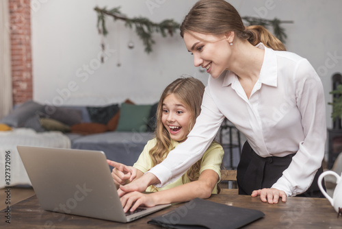 funny girl laughing with mother and computer at home