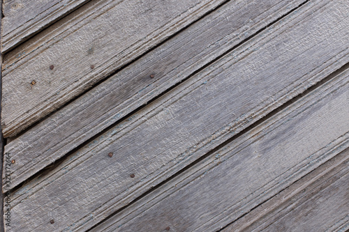 Texture of old weathered wooden fence or wall. Textured surface of brown wood (hardwood) close up. Rough grungy (grunge) background. Shabby and ragged (rugged) timber backdrop. Rustic or country view