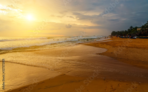 sun among clouds, beautiful yellow sunset over a sandy ocean beach of coast of Sri Lanka, Asia