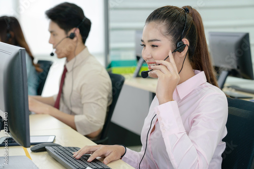 Positive female customer services agent with headset working in call center