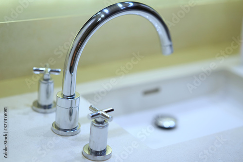 curve faucet with silver valve on side of sink or washing basin,selective focus