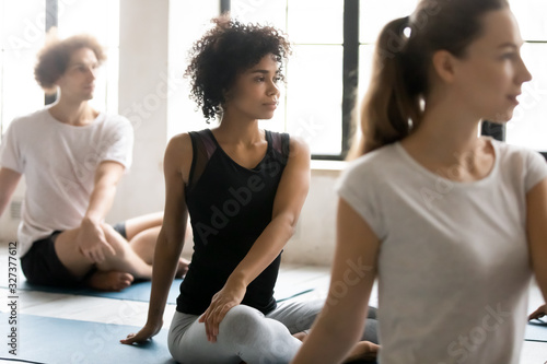 African woman with associates practicing yoga seated in lotus pose