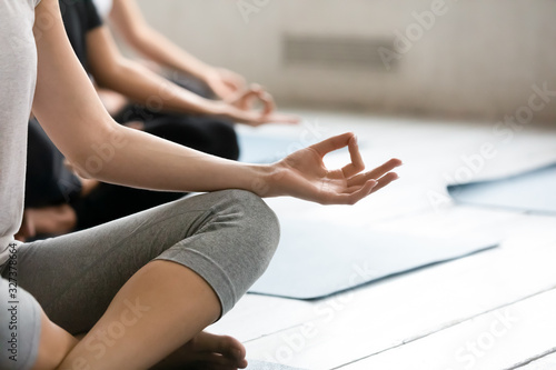 Focus on female fingers folded in mudra gesture during meditation
