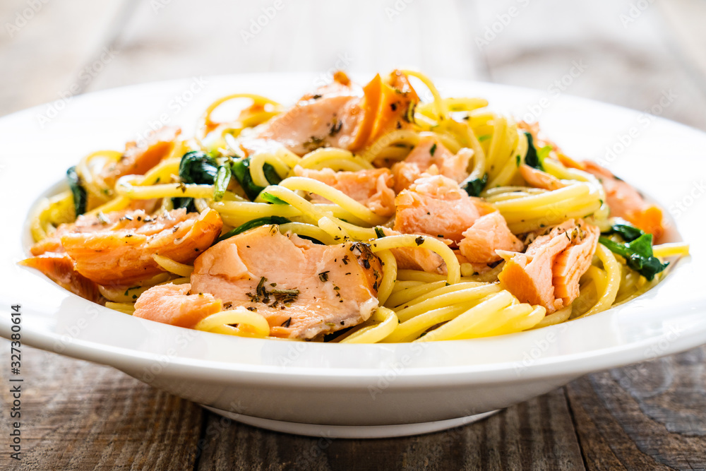 Pasta with salmon and spinach on wooden background Pasta with salmon and spinach on wooden background