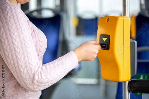 Young woman validates ticket in a public transport during transportation, transportation concept