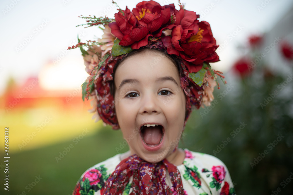 Little funny girl with a red flower crown screams with a big open mouth Little funny girl with a red flower crown screams with a big open mouth