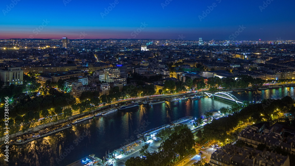 Fototapeta premium Aerial Night timelapse view of Paris City and Seine river shot on the top of Eiffel Tower