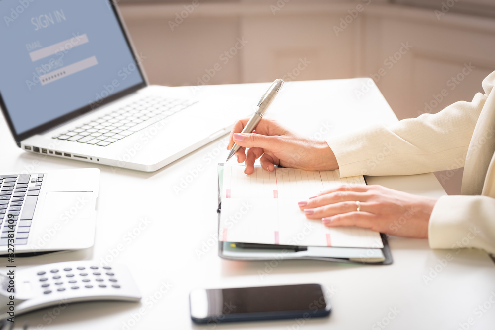 Fototapeta premium Close-up of businesswoman's hand while making note on the notebook