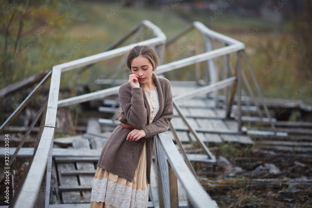 girl in vintage dress stands on a bridge