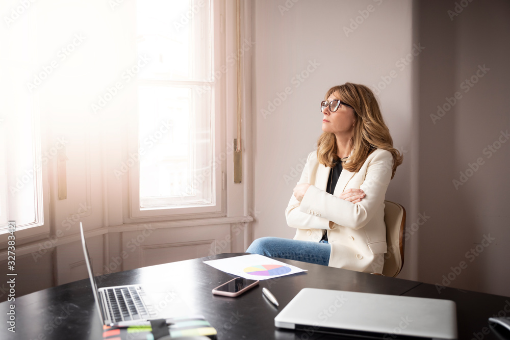 Overwhelmed businesswoman sitting by the window and thinking Overwhelmed businesswoman sitting by the window and thinking