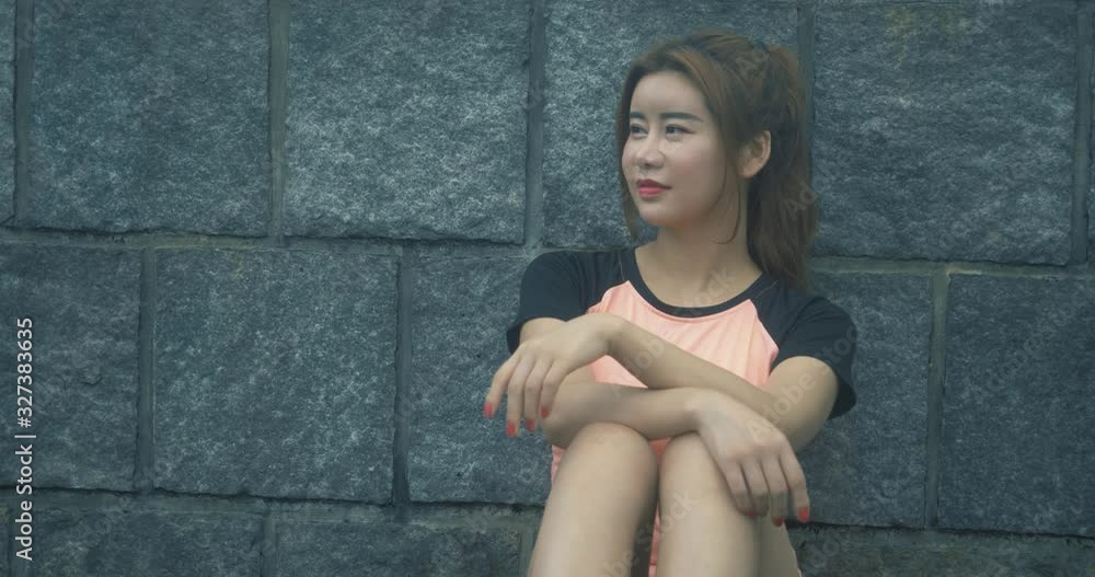 Young Chinese woman relaxing after working out in outdoor park early in the morning and living a healthy lifestyle Young Chinese woman relaxing after working out in outdoor park early in the morning and living a healthy lifestyle
