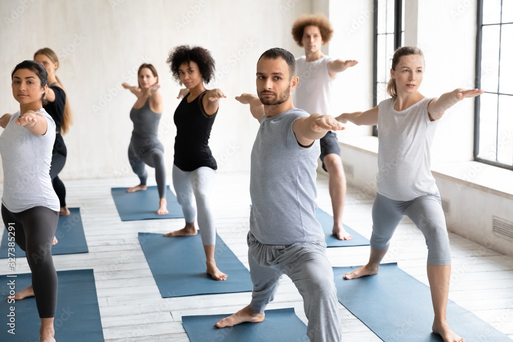 Seven multiethnic people beginners practicing yoga performing Warrior II pose Seven multiethnic people beginners practicing yoga performing Warrior II pose