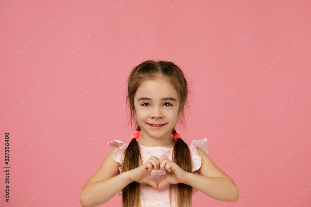 Cute smiling little child girl making heart-shape gesture on pink background. Cute smiling little child girl making heart-shape gesture on pink background.