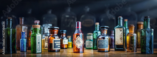 A bottle of poison on a background of old medical, chemistry and pharmacy glass. Chemistry and pharmacy history panoramic concept background. Retro style. photo