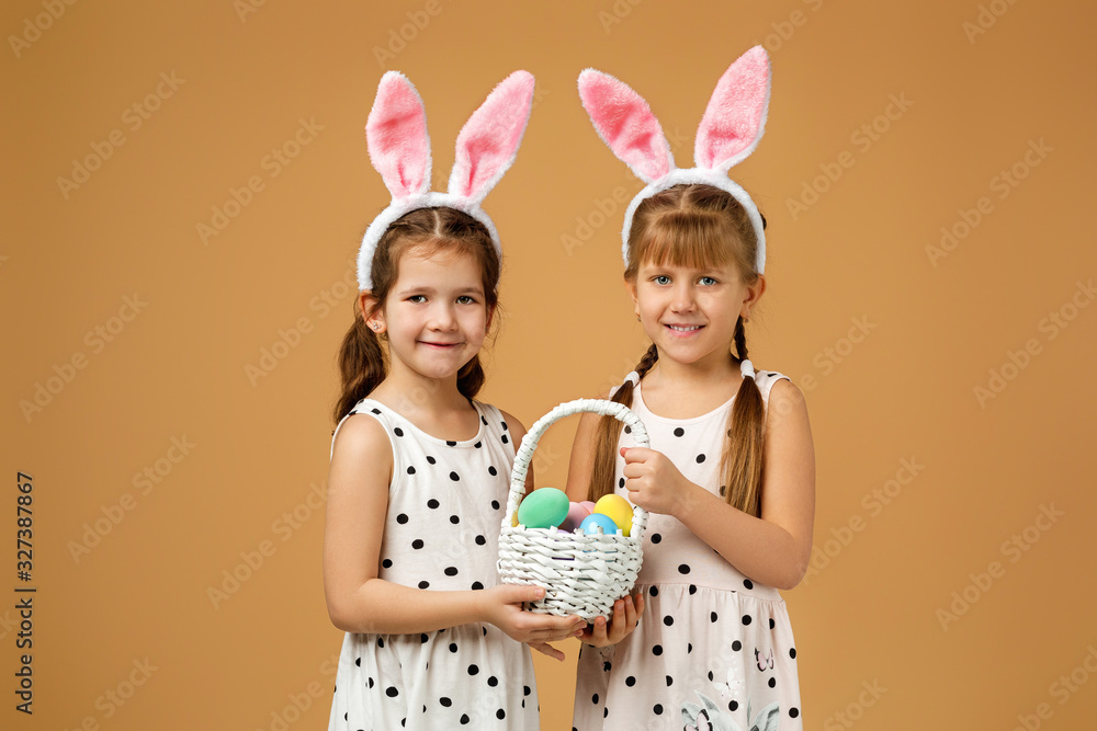 happy little child girls with pink bunny ears holding basket with painted Easter eggs on studio background. Easter day happy little child girls with pink bunny ears holding basket with painted Easter eggs on studio background. Easter day