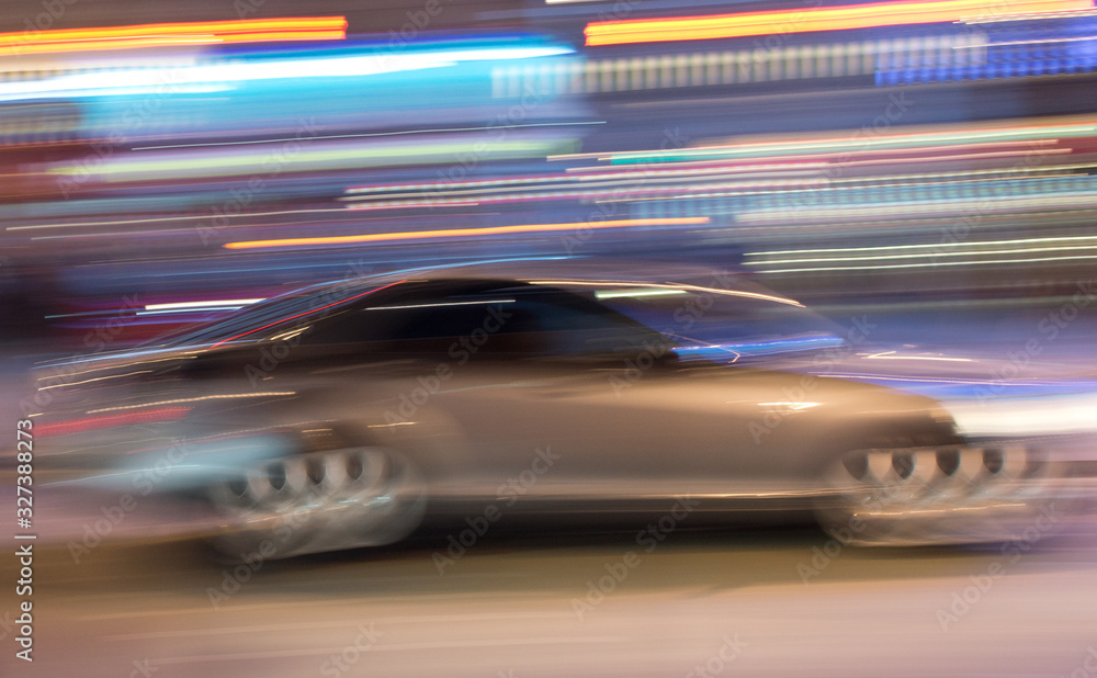 a silver grey car seen in a motion blur at night with a light streaks background a silver grey car seen in a motion blur at night with a light streaks background